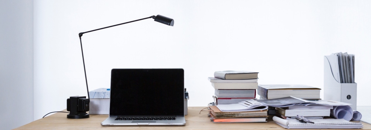 laptop on desk with books and lampshade
